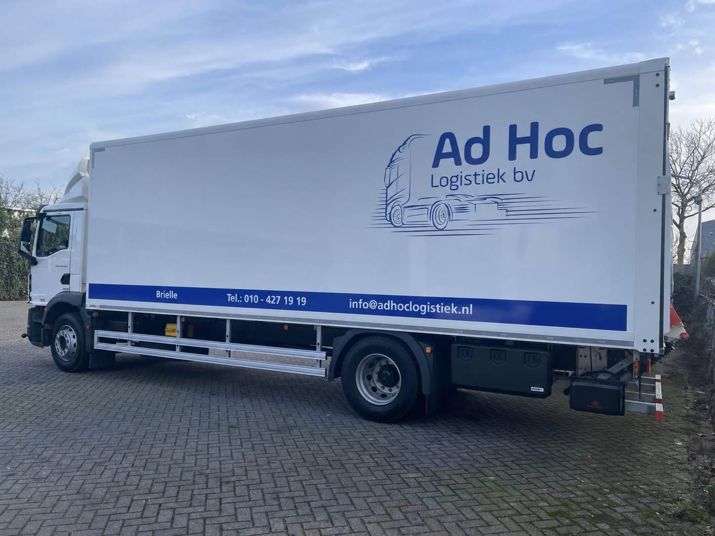 Witte vrachtwagen van Ad Hoc Logistiek met het blauwe bedrijfslogo